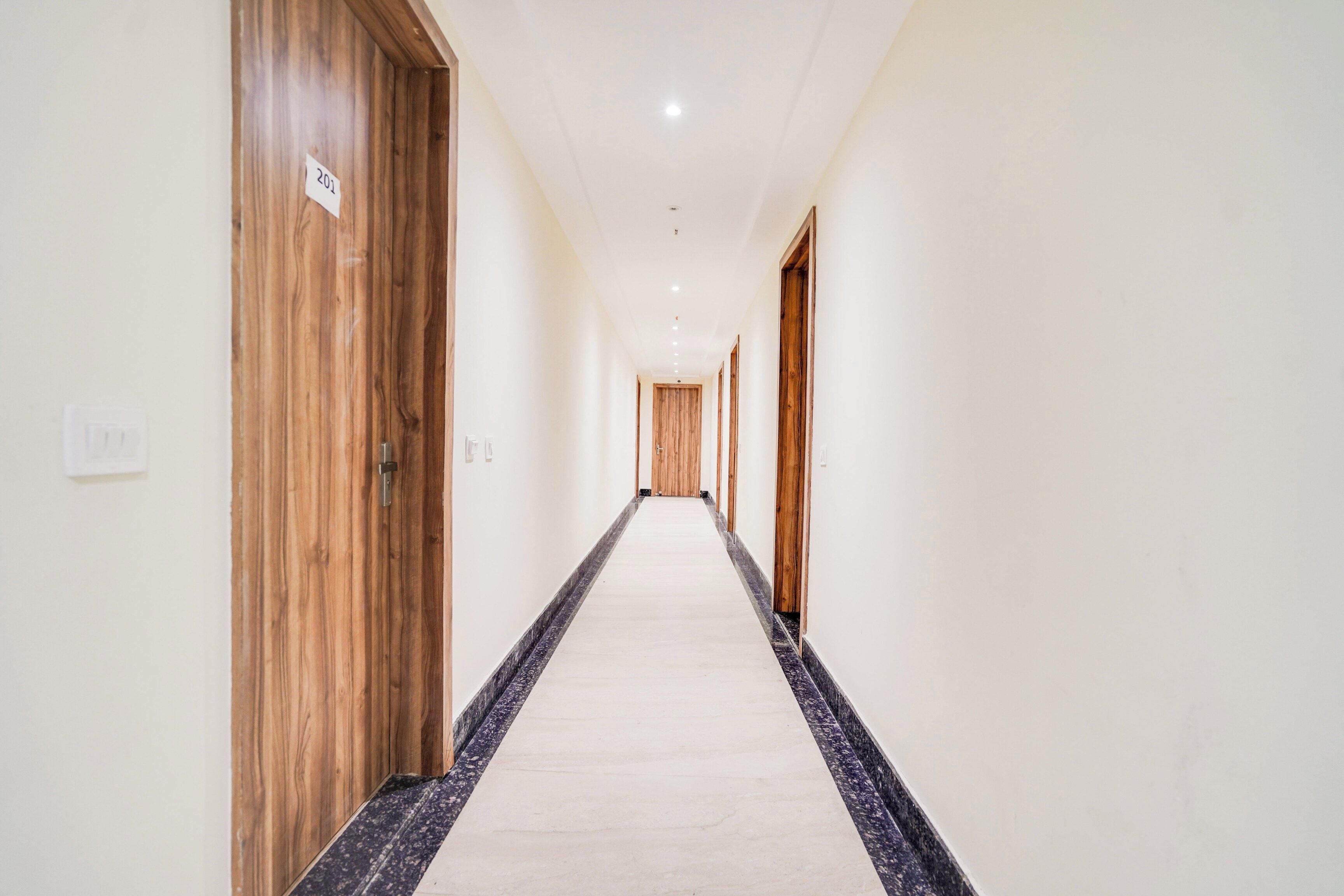 A long, narrow hallway with wooden doors on one side and a tiled floor.