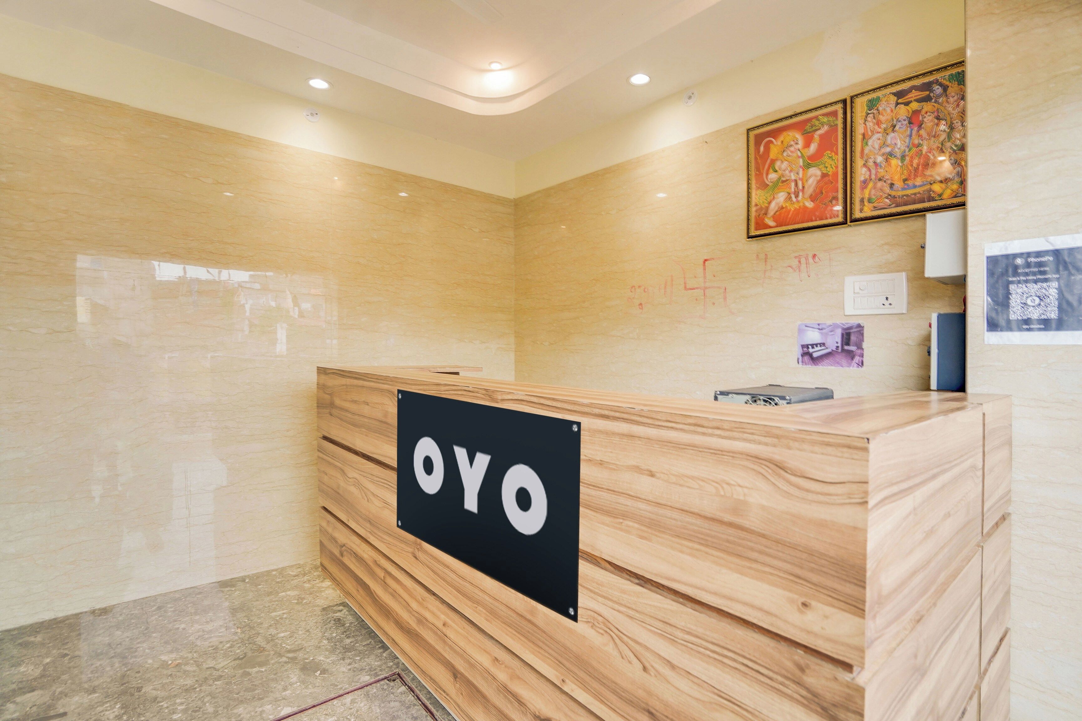 A reception desk with a sign that reads 'OYO' in a modern hotel lobby with marble walls and ceiling lights.