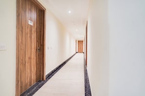 Ein Hotelgang mit Holztüren, einem Marmorboden und einer weißen Wand.