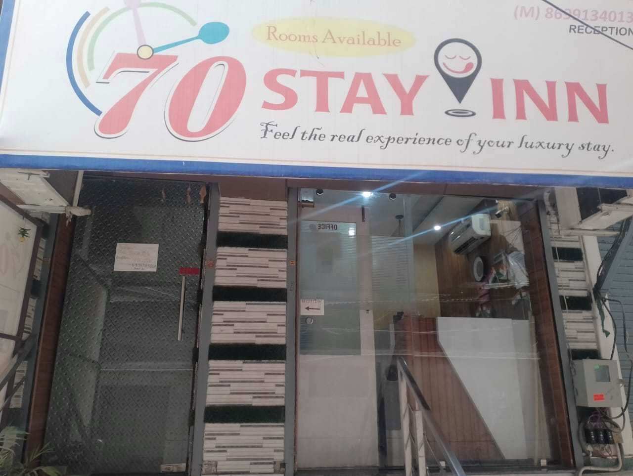 L’entrée d’un hôtel, avec une enseigne indiquant « Chambres disponibles » et « 70 STAY INN ».
