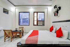 Habitació d'hotel amb un llit, una taula de menjador amb cadires i dues finestres.