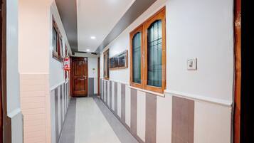 Un couloir avec une porte en bois, un extincteur et un interrupteur sur le mur.