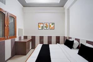 Une chambre d’hôtel comprenant un lit, une table de chevet, une armoire et trois œuvres d’art encadrées accrochées au mur.