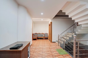 A hallway with a wooden bench, a staircase, and a wall-mounted light fixture. - Hotel O City View (Jabalpur)