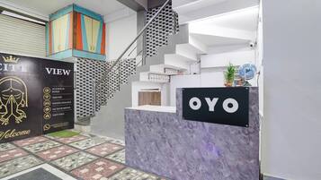A reception area with a marble counter, a staircase with a metal railing, and a colorful cabinet.