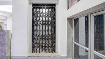 A building entrance with a metal gate, a tiled floor, and a glass door.