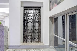A building entrance with a metal gate, a tiled floor, and a glass door. - Hotel O City View (Jabalpur)