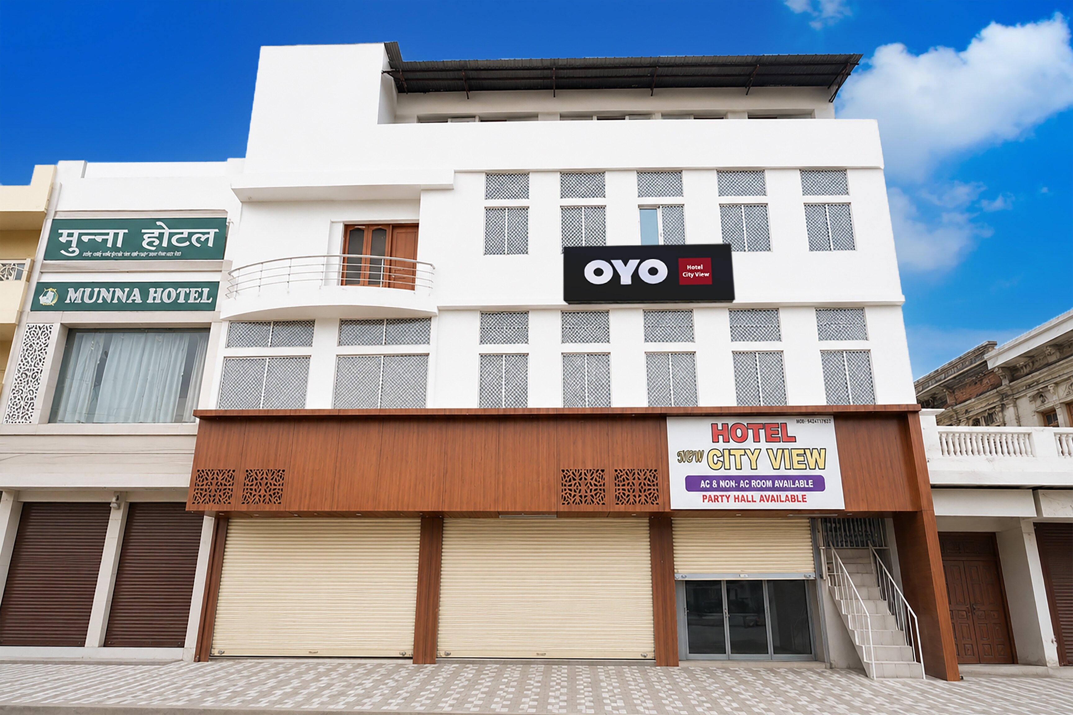 A hotel with a sign for 'MUNNA HOTEL' and 'OYO Hotel City View' indicating available rooms and a party hall.