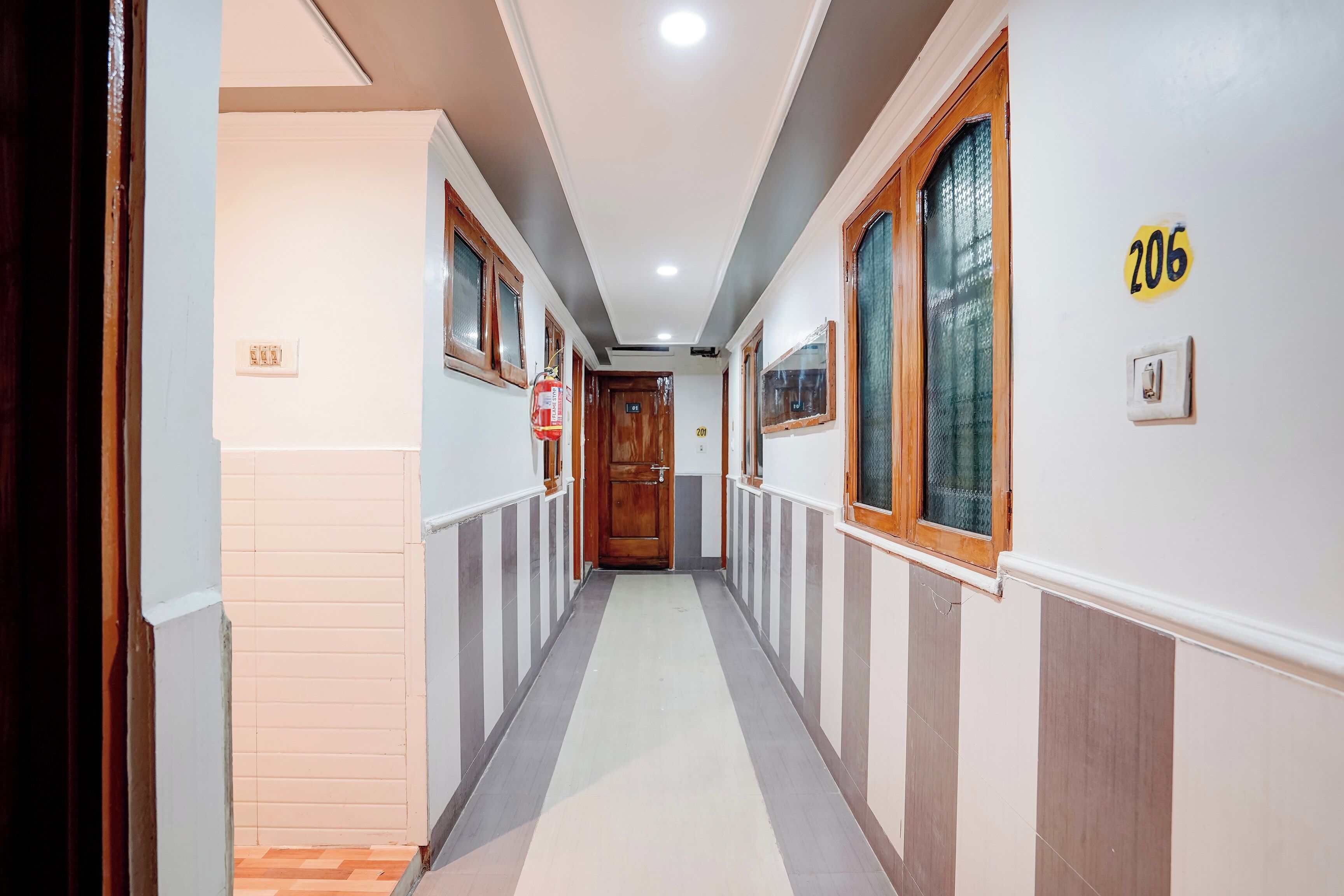 A corridor with doors numbered 201 and 206, a fire alarm, and a light switch on the wall.