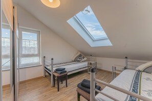 Une chambre avec un puits de lumière, un lit, un banc et une fenêtre.