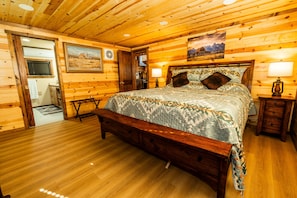 A wooden cabin bedroom with a large bed, a wooden floor, and a painting on the wall. - Kent's Knoll - Inspired by the iconic landscape of the Black Hills. (Newcastle)