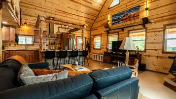 Interior de una cabaña de madera con sala de estar, cocina y comedor.