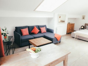 A modern living room with a dark blue sofa, orange cushions, a wooden coffee table, and a fruit bowl. - House Luna - Apartment Luna 8 (Schwangau)
