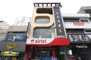 Un hotel con un llamativo letrero de 'Airtel', un letrero de 'Pearl Hotel' y varios otros letreros de negocios, incluyendo 'Caletto' y 'People'.
