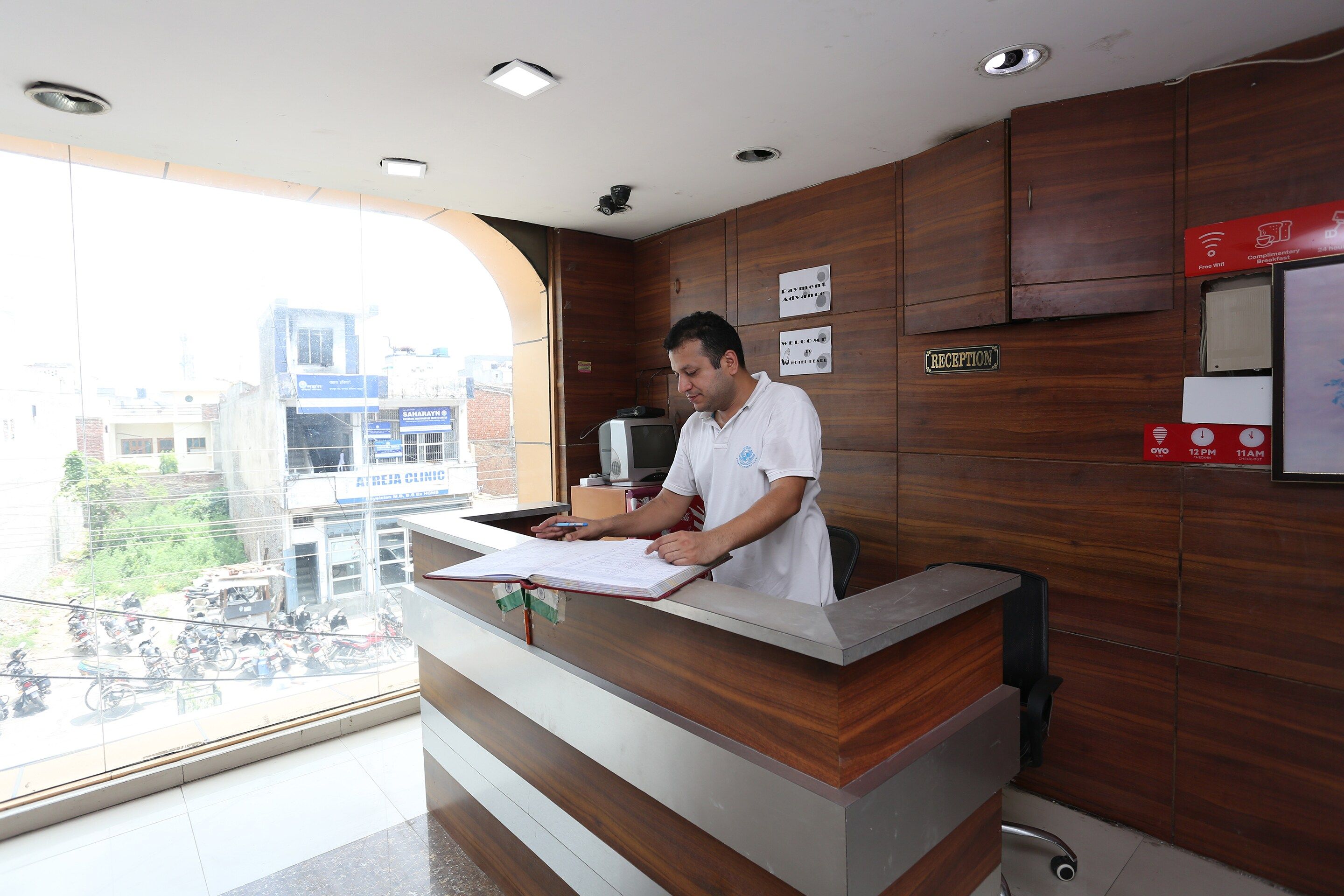 A reception desk with a city view, a sign indicating complimentary breakfast, and a sign for payment advance.