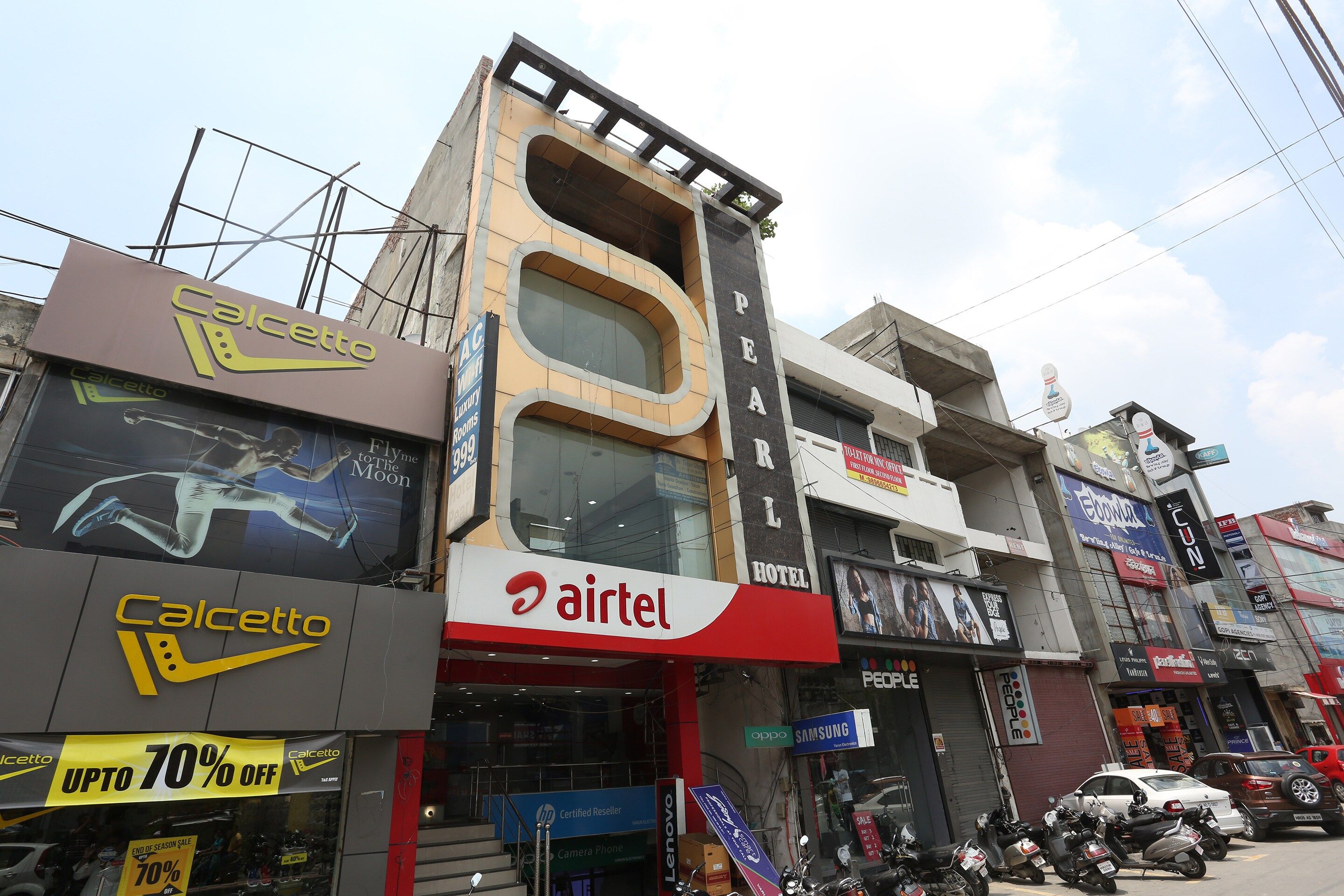 A multi-story building with a prominent Airtel sign, a Caletto store, and a sign for a hotel.