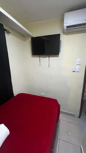 A room with a bed, a mounted television, an air conditioning unit, and a wall socket. - New Listing (Santiago de los Caballeros)