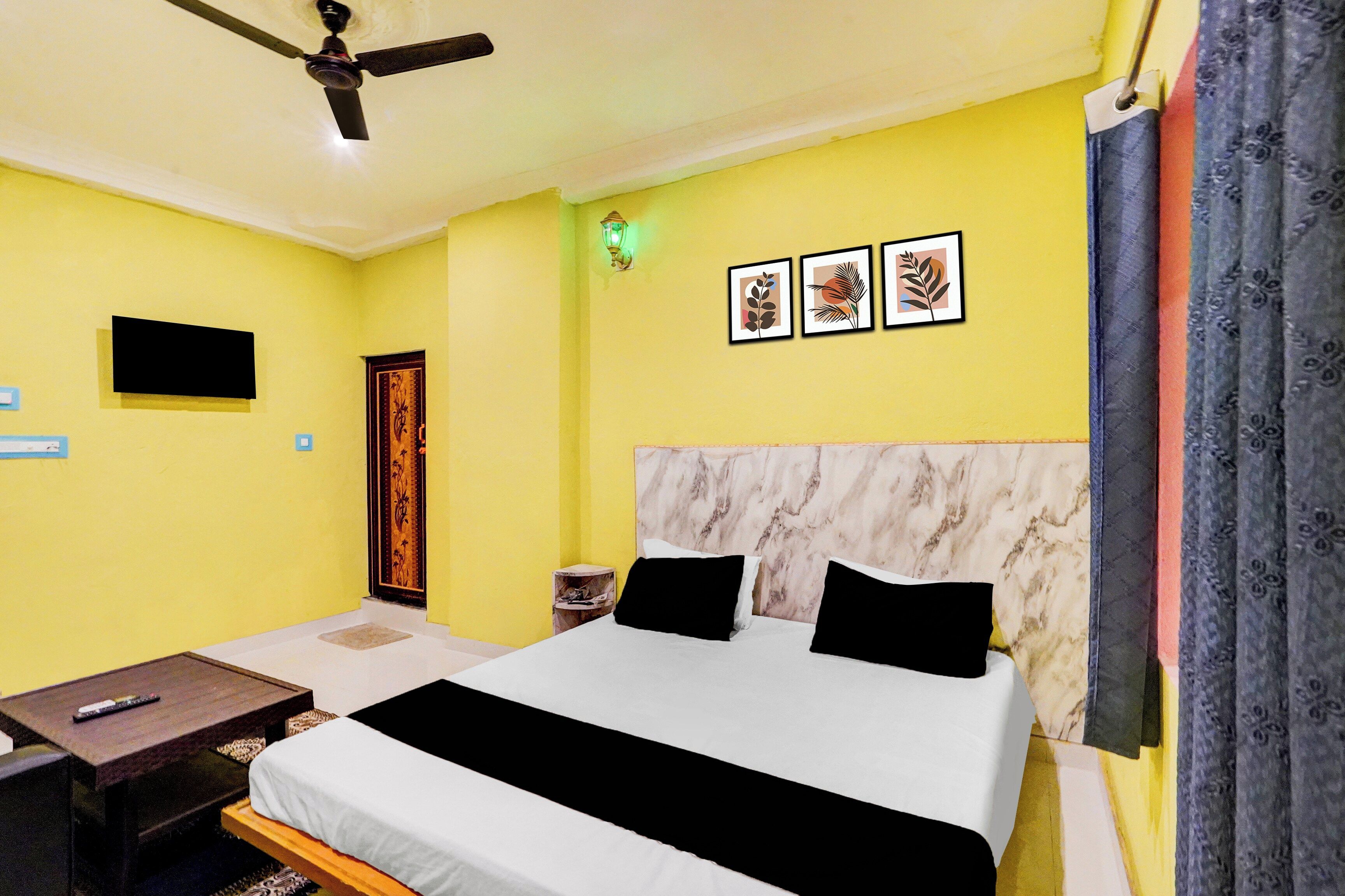 A hotel room with a bed, a desk, a chair, a television, and a ceiling fan.