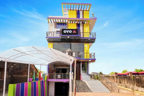 A multi-story hotel with a prominent sign, a covered outdoor area, and a staircase leading to the entrance.