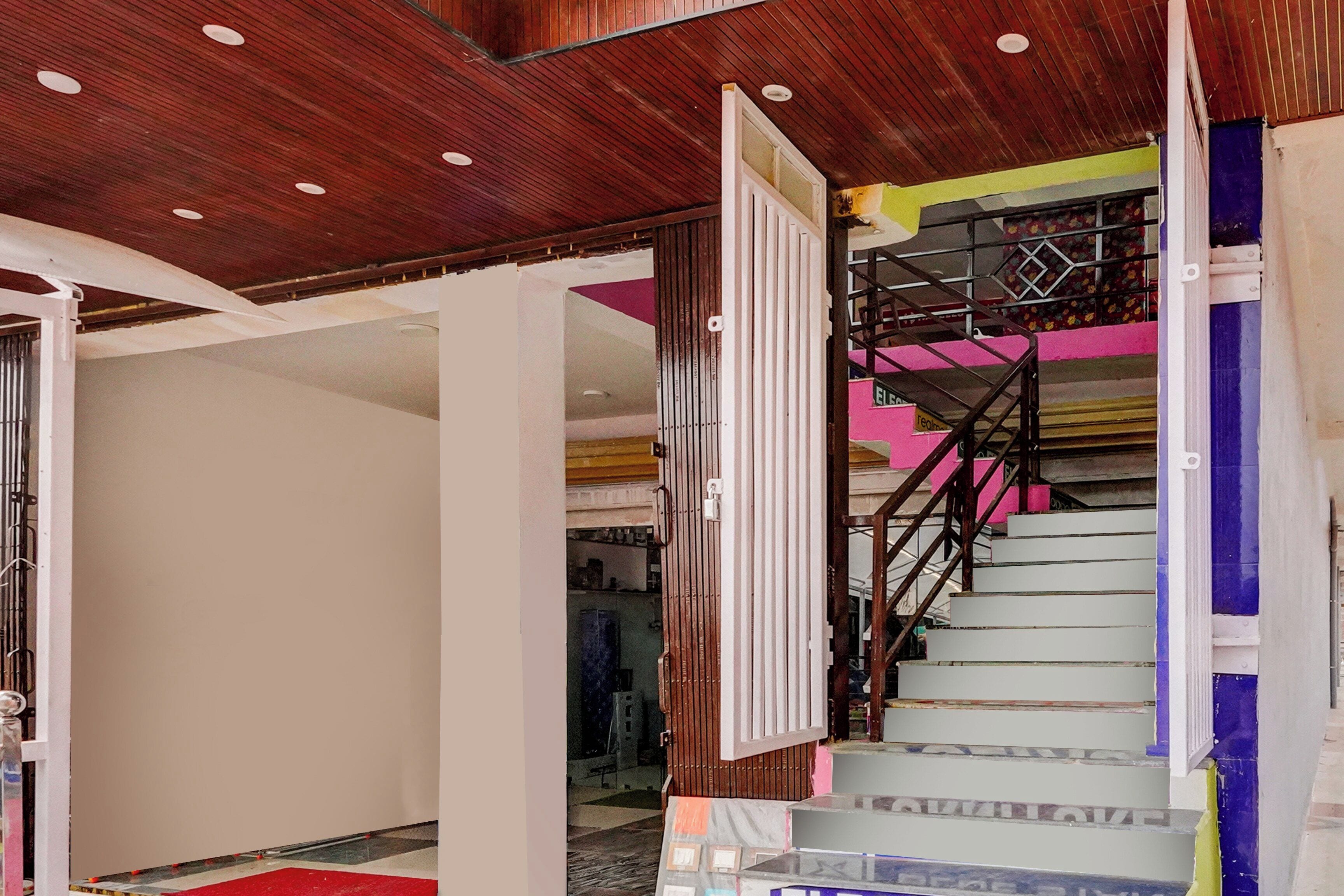 A staircase with a metal railing and a red carpet leading up to it.