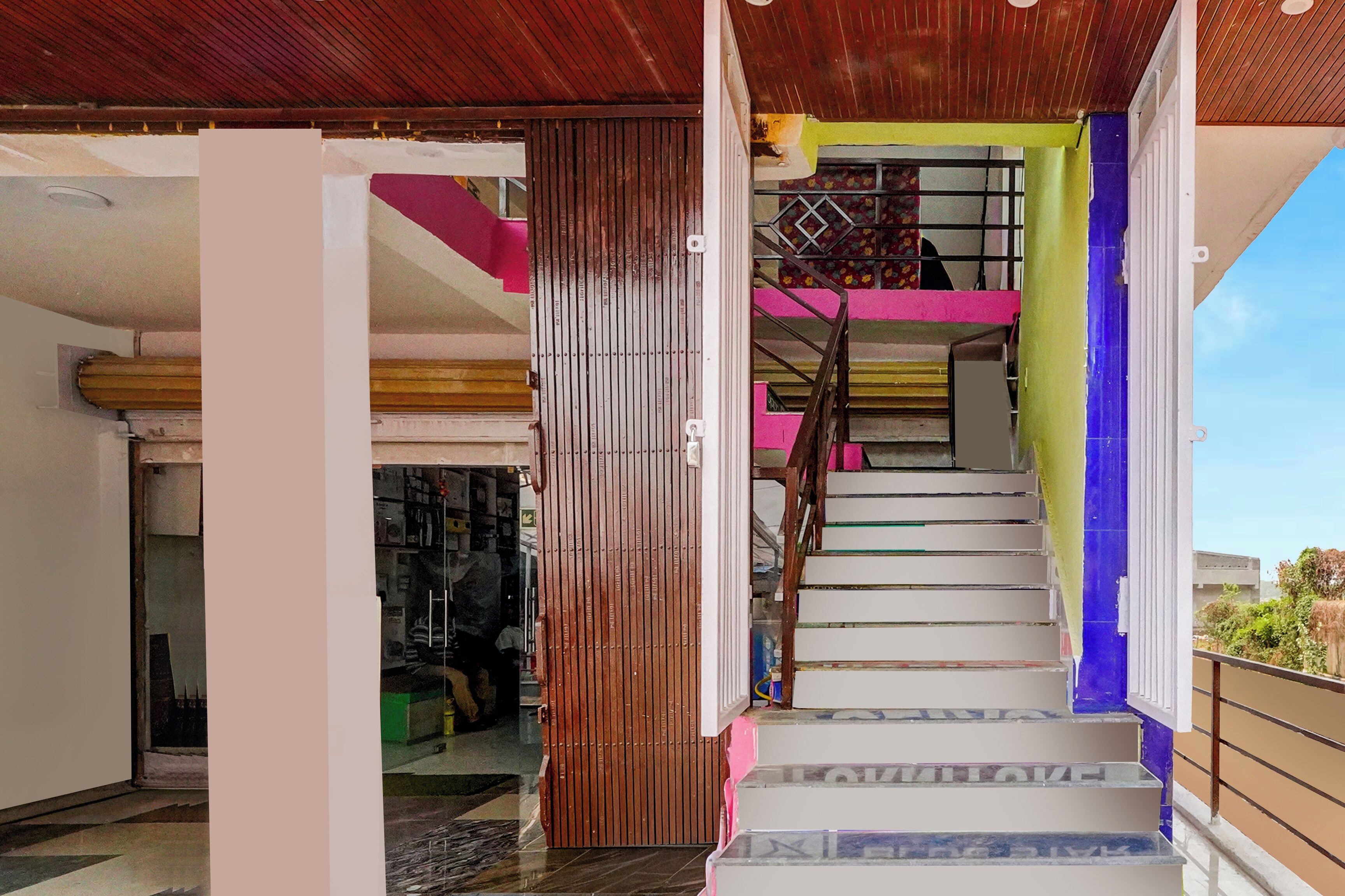 A staircase with white steps and a wooden handrail, leading to a balcony with a view of the sky.