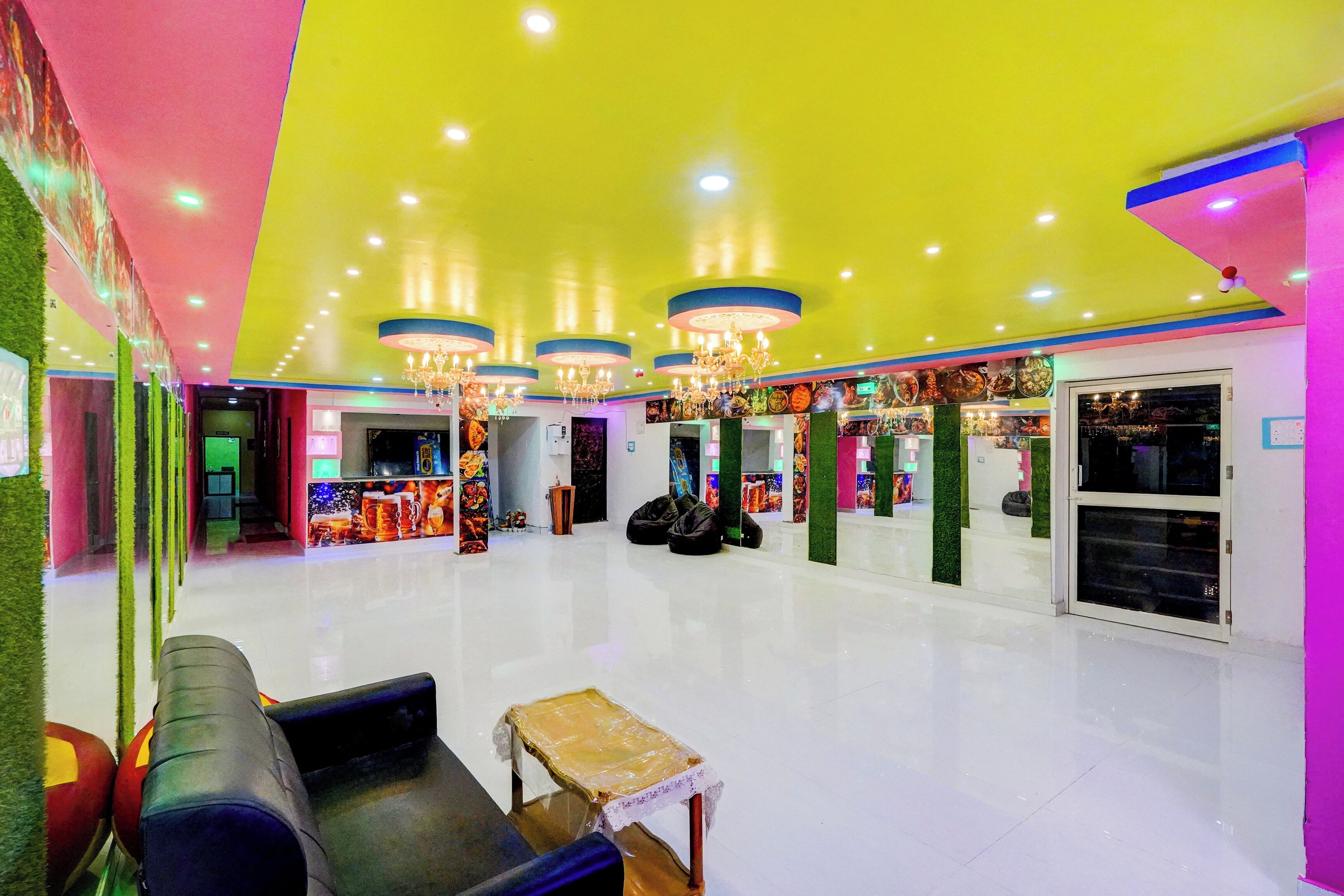 A brightly lit indoor space with a seating area, chandeliers, and a wall with various items displayed.