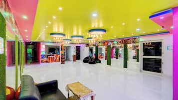 A brightly lit indoor space with a seating area, chandeliers, and a wall with various items displayed.