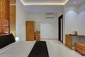 Una habitación de hotel con una cama, un escritorio, un espejo y un equipo de aire acondicionado.