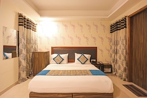 Ein Hotelzimmer mit einem großen Bett, einem Holzkopfschild und Vorhängen mit Baum-Motiven.