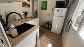 Een kleine keuken met een spoelbak, een magnetron en een koelkast.