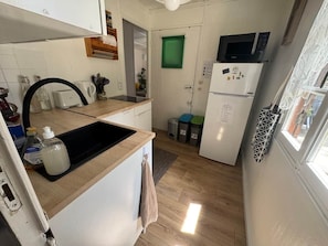 Cozinha compacta com pia, micro-ondas e geladeira.
