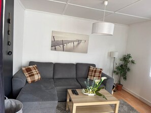 Un salon moderne avec un canapé gris, une table basse en bois et un tableau accroché au mur.