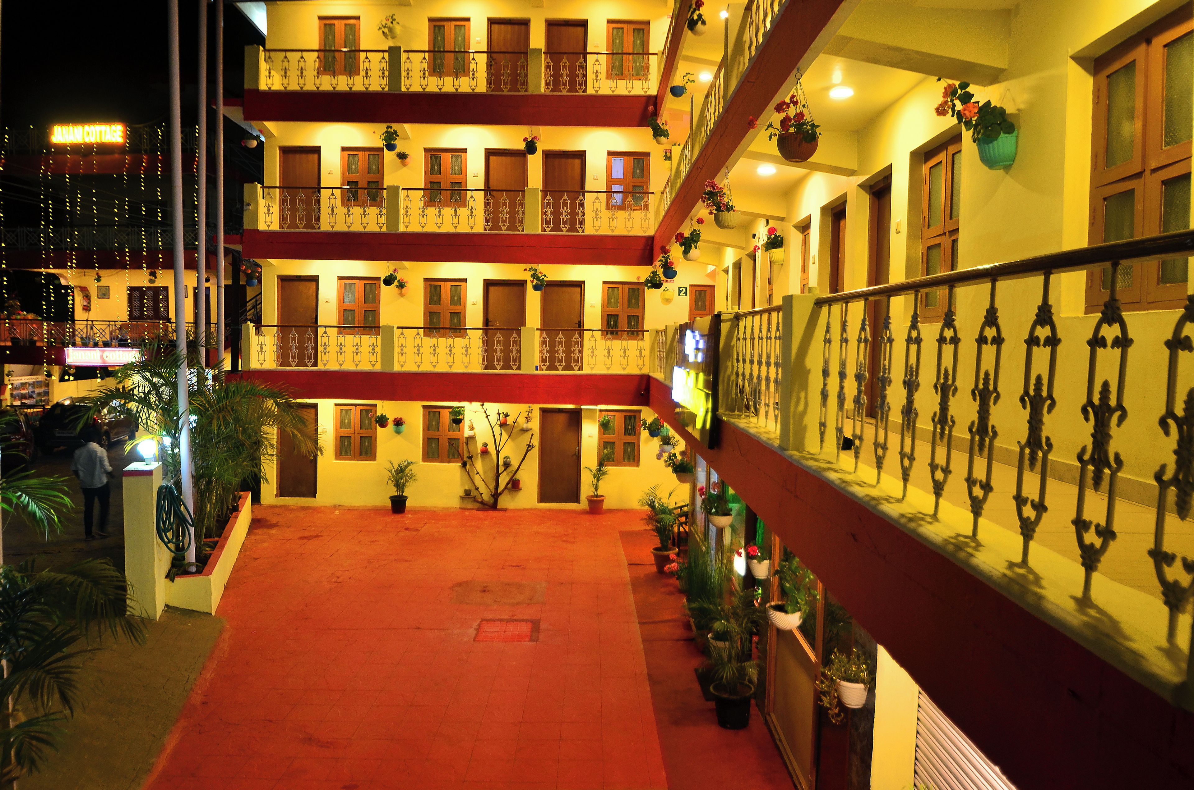 A multi-story hotel with balconies, potted plants, and a red carpeted walkway.
