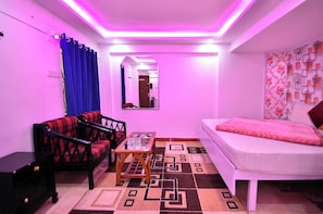 Een kamer met een bed, een bank, een stoel, een tafeltje en een kamerbreed tapijt met een patroon.