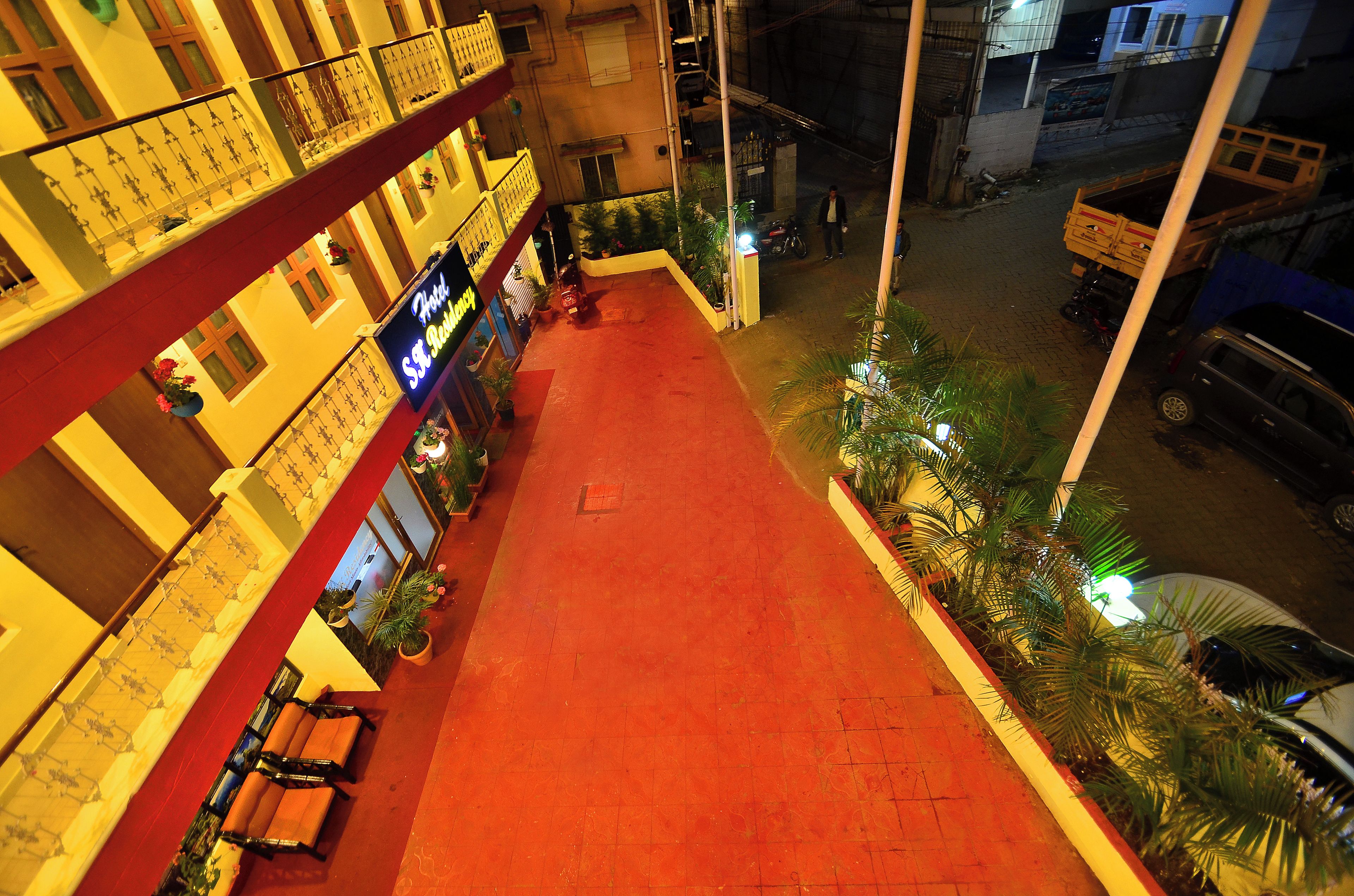 A hotel corridor with a red carpet, potted plants, and a sign for the hotel.