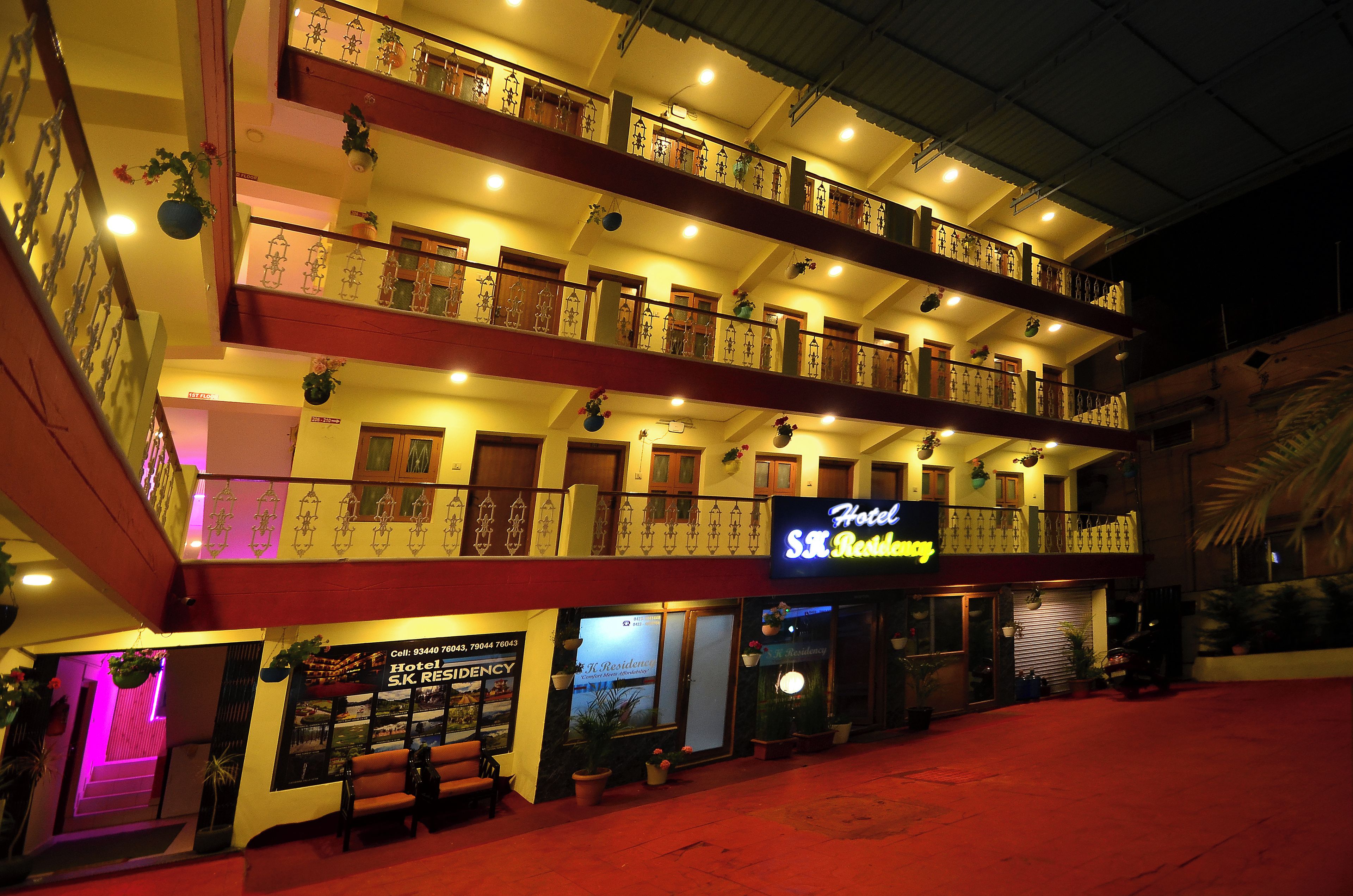 A multi-story hotel with balconies, a neon sign, and a red carpeted entrance.