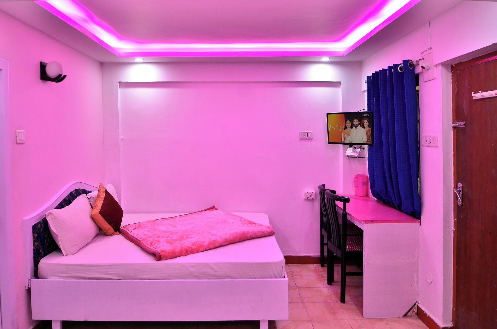 A room with a bed, a desk, and a television.