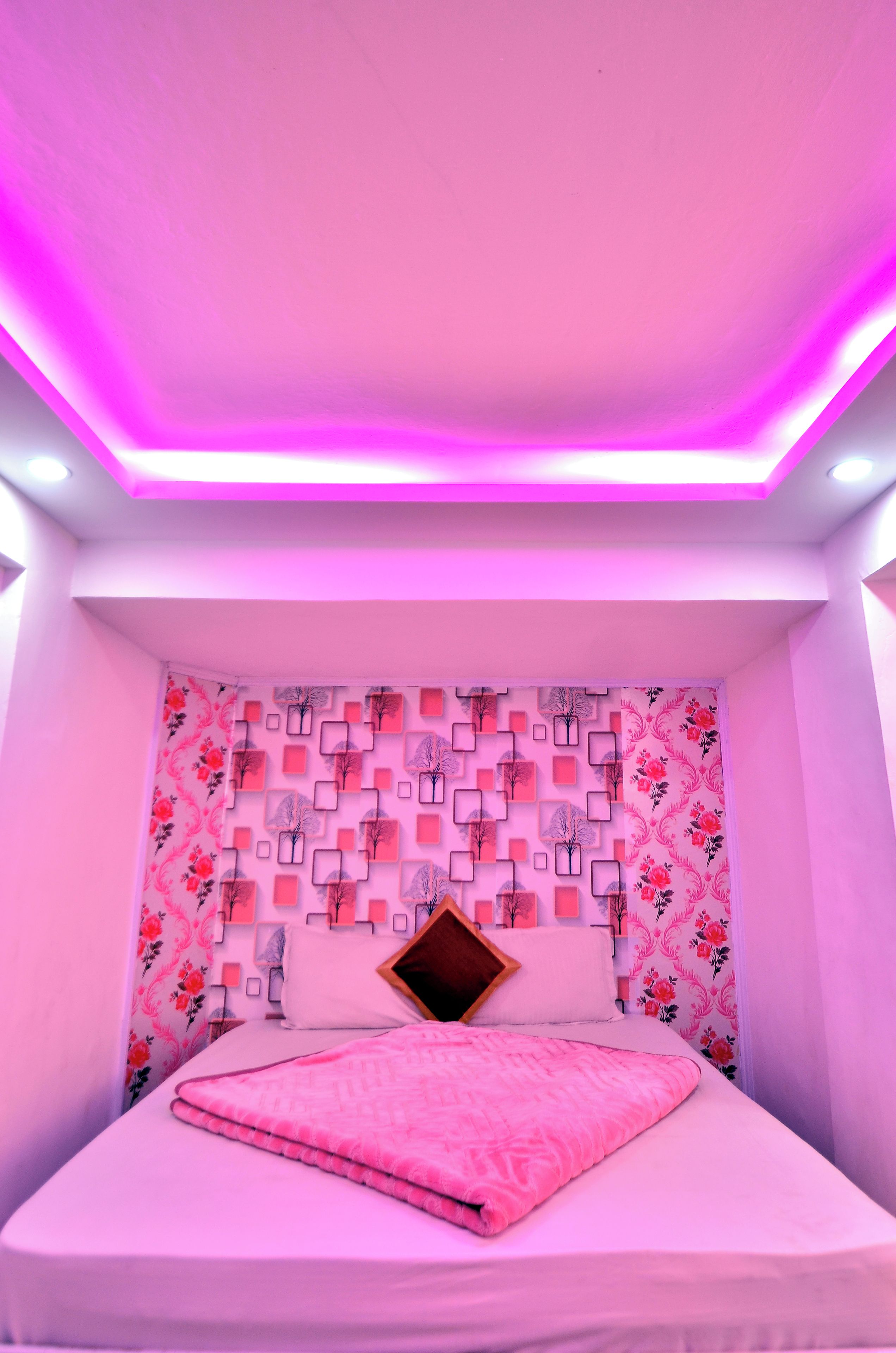 A bedroom with a bed, a patterned wall, and a ceiling light.