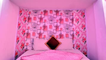 A bedroom with a bed, a patterned wall, and a ceiling light.