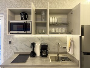 A modern kitchen with a built-in microwave, coffee maker, and a stainless steel sink. - New Listing (San Nicolas)