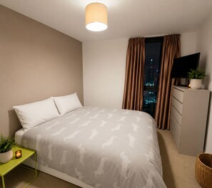 A modern bedroom with a bed, a dresser, a television, and a window with curtains. - Amazing apartment near London Bridge, Tower Brigdge and City of London (London)