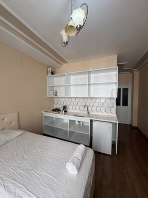Une chambre avec un lit, une petite kitchenette et une salle de bain.
