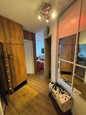 A narrow hallway with wooden cabinets, a bench, and a door leading to another room. - Appartement cosy – aux 2 Alpes (Les Deux Alpes)