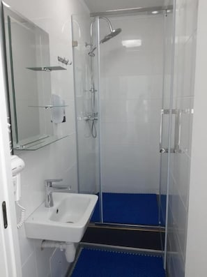 Ein modernes Badezimmer mit einer Duschkabine, einem weißen Waschbecken und einer blauen Duschmatte.