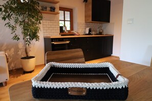 Una cocina con una mesa de madera, una planta en maceta y una bandeja blanco y negro de crochet sobre la mesa.