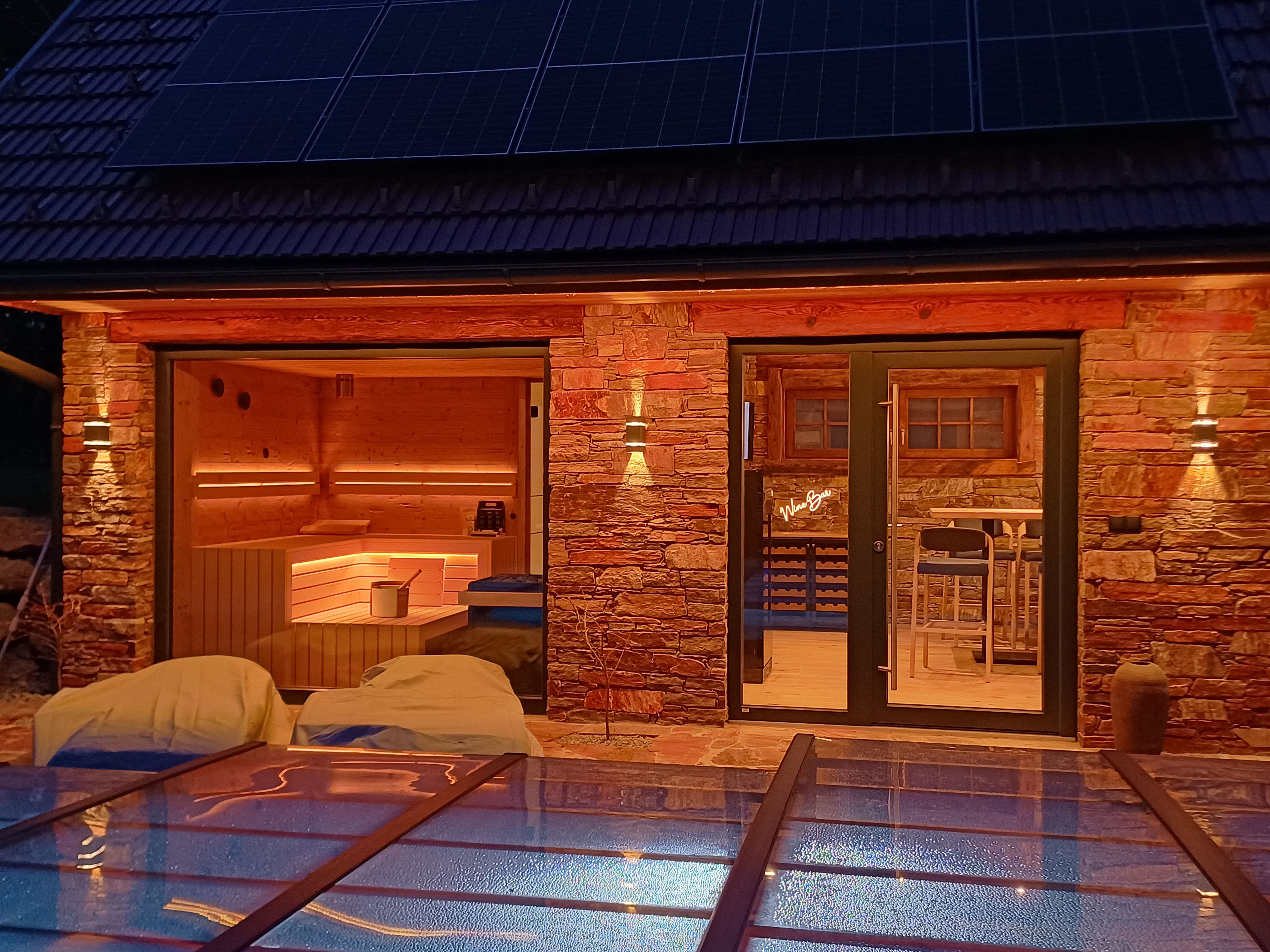 Een wellnessruimte met een sauna, een massagetafel en een overdekt zwembad.
