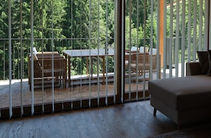 A room with a large sliding glass door leading to an outdoor balcony with wicker furniture and a table.