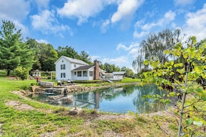 A house with a pond, a gazebo, and a well-maintained lawn.