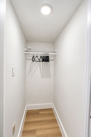 Un pasillo estrecho con techo blanco, suelo de madera y una pared blanca con un perchero.