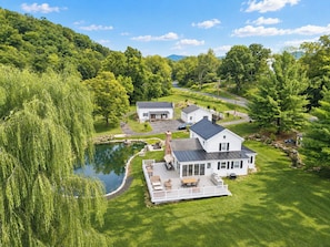 A residential property with a large house, a smaller building, a pond, and a well-maintained lawn.